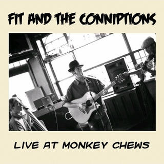 A black and white photo of a three piece band, with Wayne in the middle, on guitar, wearing a trilby, looking at Hezron on the right, who is playing fiddle, wearing a flat cap, with Paul, on electric upright bass on the left. Paul is hatless. The whole thing is at a rakish angle, so Paul appears to be lower than Hezron is.